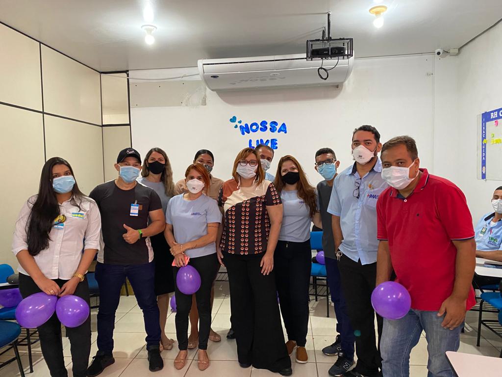 Na foto aparecem vários colaboradores do Hospital Municipal de Araguaína. Eles estão lado a lado de frente para a câmera. Todos usam máscara e alguns seguram balão roxo nas mãos.