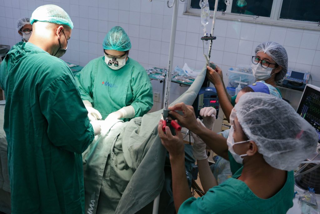 Dois médicos realizam a cirurgia e duas pessoas ajudam com os equipamentos